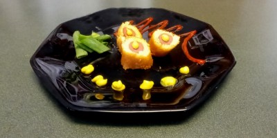 Corn dog with tomato, vinegar, and corn syrup reduction, our signature mustard sauce, and salade de tondeuse à gazon